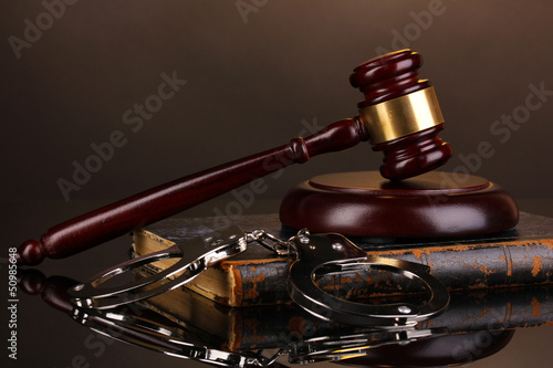 Gavel, handcuffs and.book on law on brown background