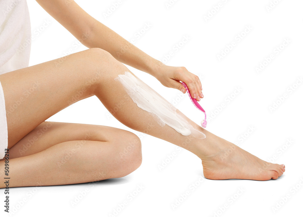 Beautiful woman is shaving her leg, isolated on white Beautiful woman is shaving her leg, isolated on white