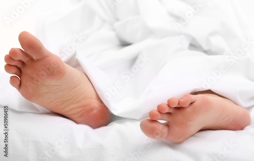 Beautiful feet of a young woman lying in bed close up