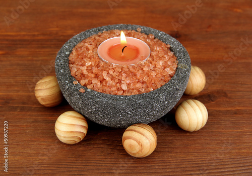 Candle in stone bowl with marine salt, on wooden background