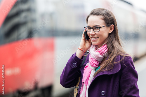 Fototapeta Naklejka Na Ścianę i Meble -  Young Woman Talking on Mobile at Train Station