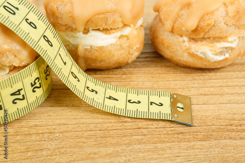 concept of slimming, caramel cakes with measuring tape