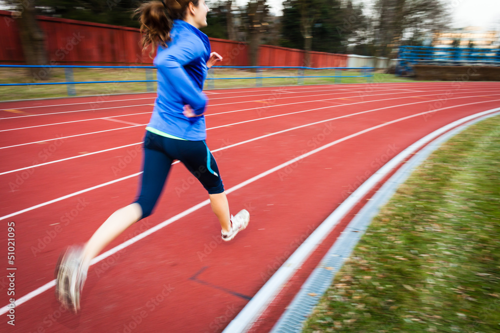 Obraz premium Young woman running at a track and field stadium