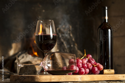 Copas de vino tinto, botella uvas y corcho.