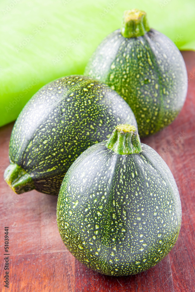 Round green zucchini on wooden table Round green zucchini on wooden table