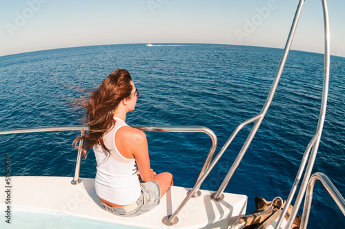 Fototapeta Naklejka Na Ścianę i Meble -  Wide angle view of pretty young woman sitting on shipboard