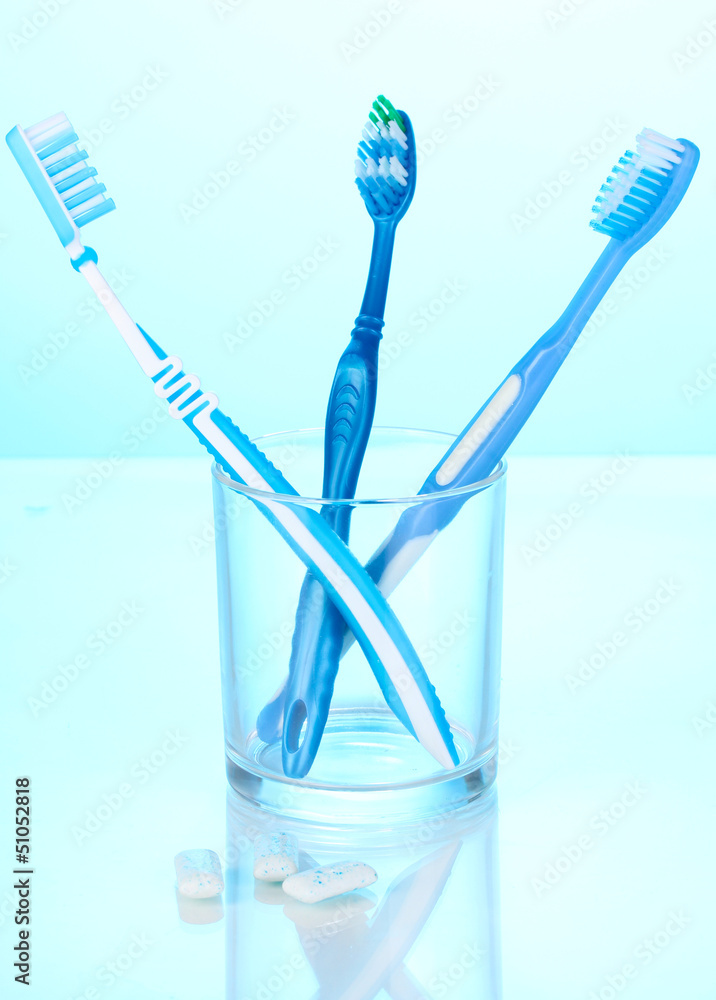 Toothbrush in glass and chewing gum on blue background