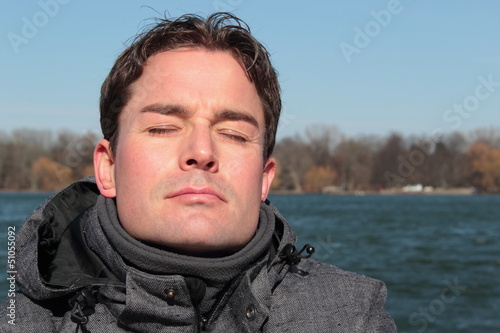 Mann relaxt im Winter im Sonnenschein am See