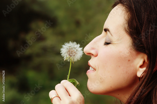 portrait young woman blowing dandelion