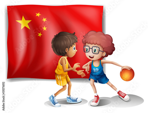 Two boys playing basketball in front of the flag of China