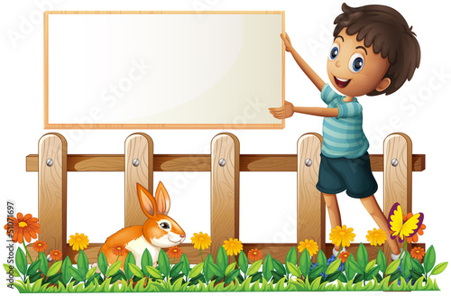A boy holding a framed board in the garden