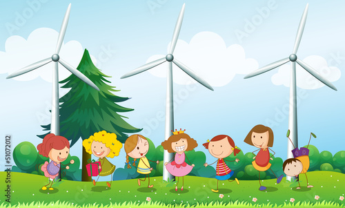Seven kids playing in the hill with three windmills