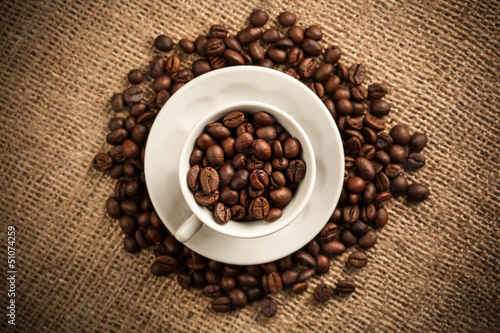 Roasted coffee beans in a cup on burlap background