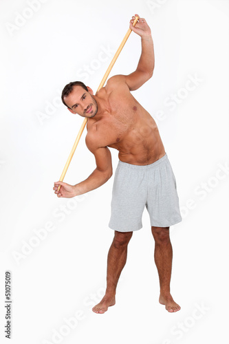 Man exercising with a wooden stick