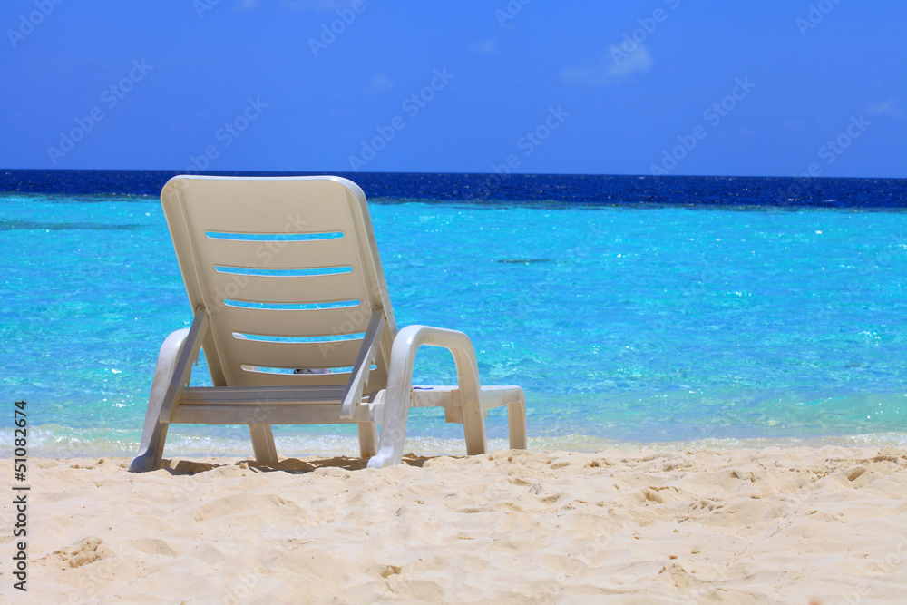 Liegestuhl am Strand einer tropischen Insel