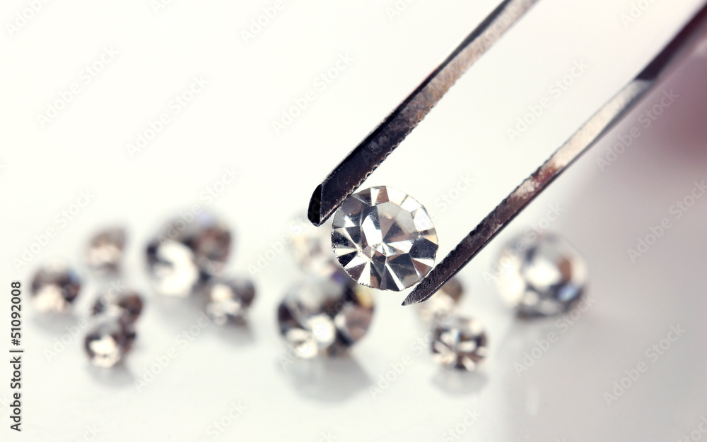 Beautiful shining crystal (diamond) in the tweezers, isolated Beautiful shining crystal (diamond) in the tweezers, isolated