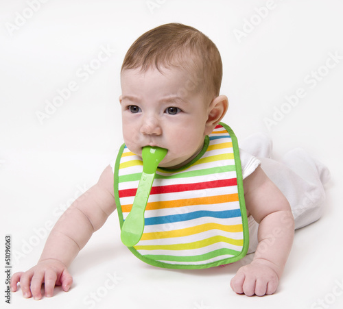 Baby with spoon in mouth looking aside