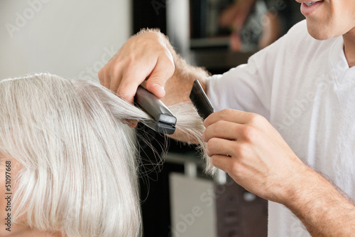 Hairstylist straightening woman's hair