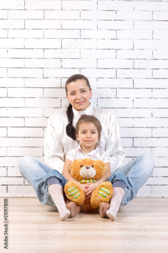 Mother and daughter sitting, holding a toy