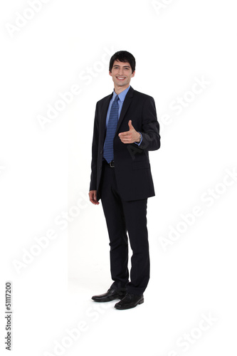 Young businessman giving thumbs-up gesture