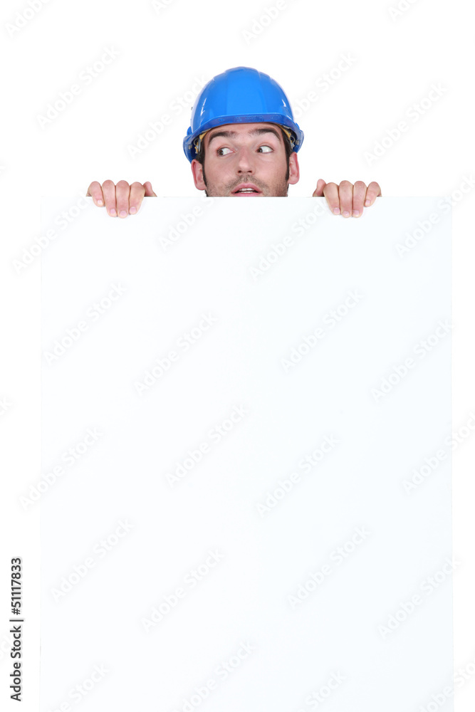 A construction worker hiding behind a poster. A construction worker hiding behind a poster.