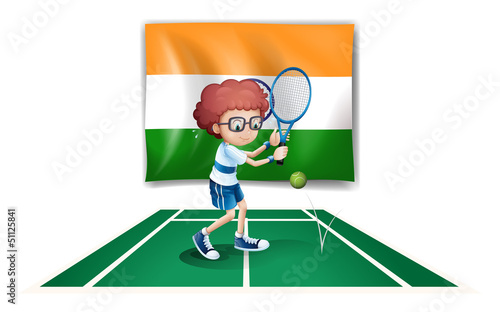 A boy playing tennis in front of the Ireland flag