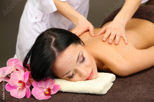 Beautiful young woman in spa salon getting massage with spa