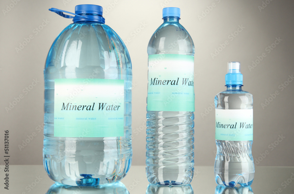 Different water bottles with label on grey background Different water bottles with label on grey background