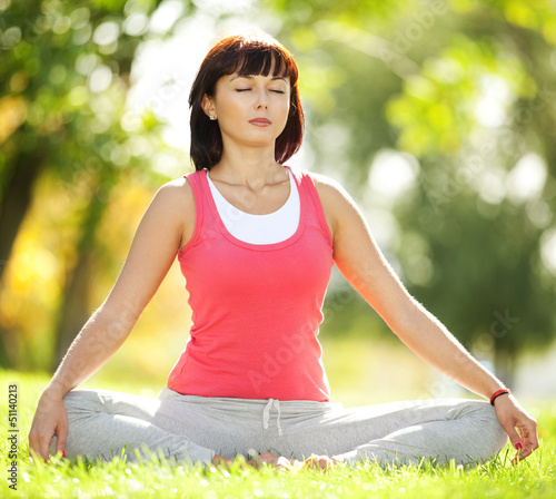 Pretty woman doing yoga exercises in the park