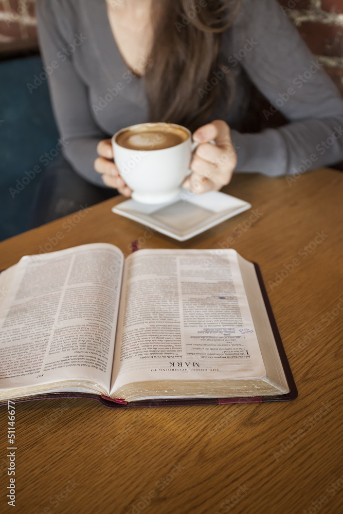 Young Woman with White Coffee Cup Reads Her Bible