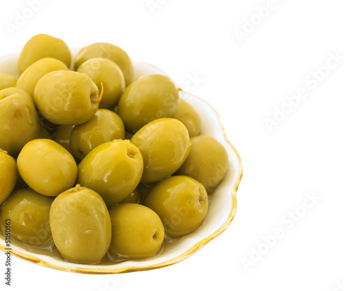 Green salt olives in a white dish with leaves isolated on white