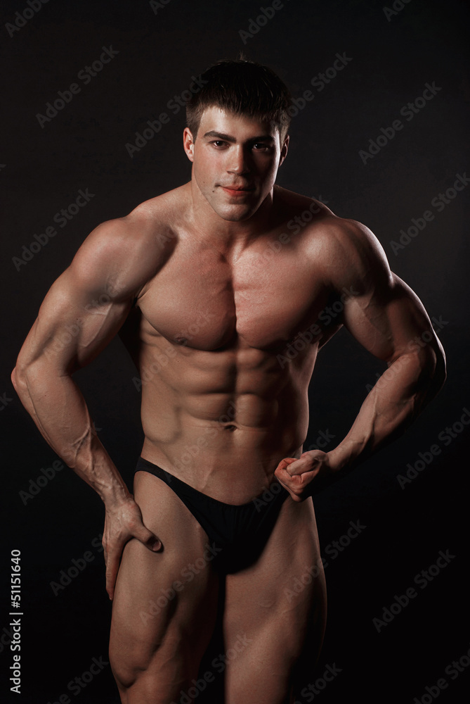 Young attractive man in a black bathing suit bodybuilder