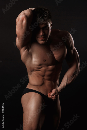 Young attractive man in a black bathing suit bodybuilder