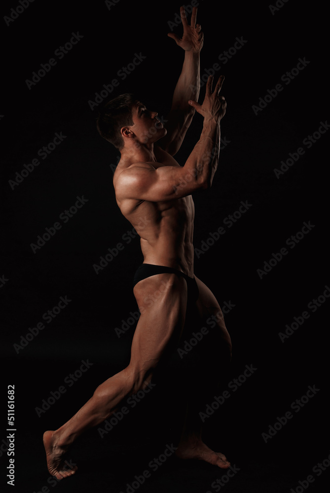 Naklejka premium Young attractive man in a black bathing suit bodybuilder