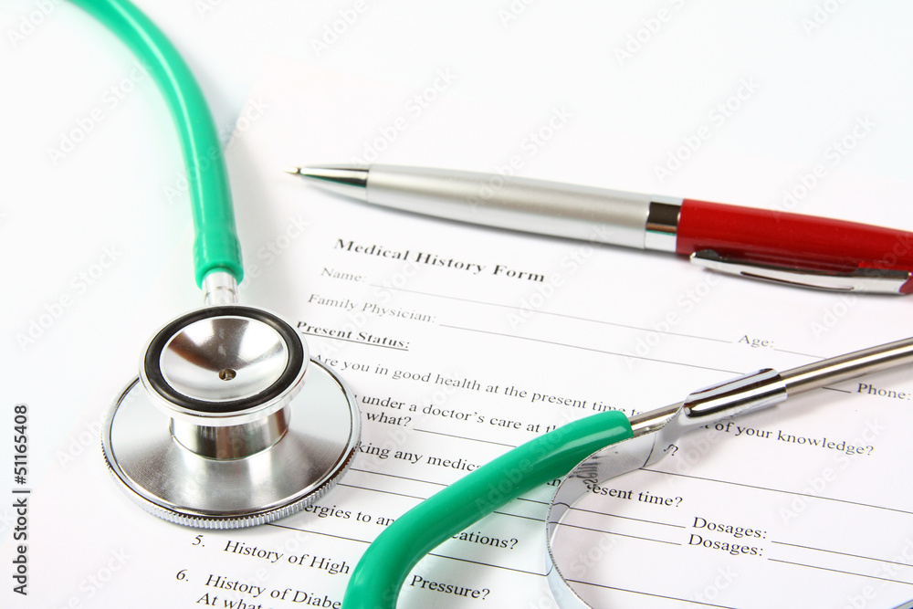 Green stethoscope and a red pen lying on a medical history form Green stethoscope and a red pen lying on a medical history form