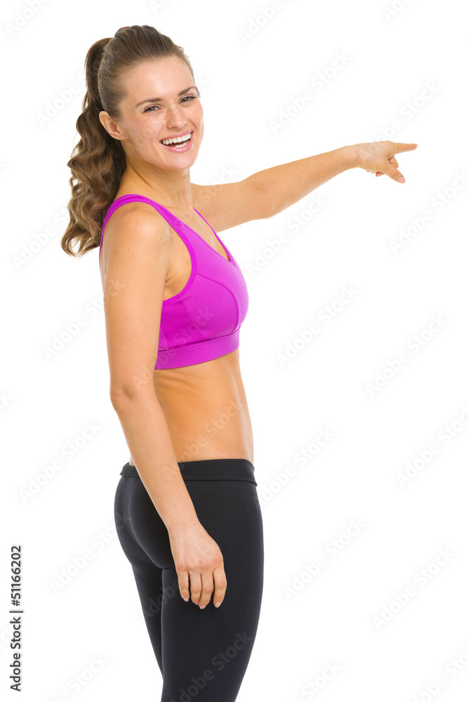 Smiling fitness young woman pointing on copy space Smiling fitness young woman pointing on copy space