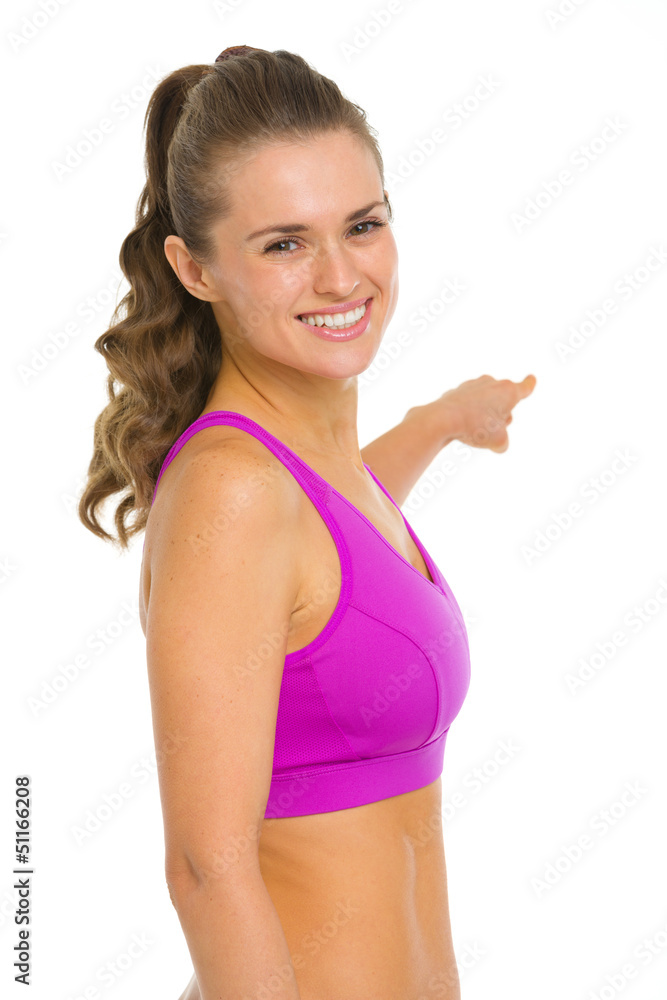 Portrait of smiling fitness young woman pointing on copy space Portrait of smiling fitness young woman pointing on copy space