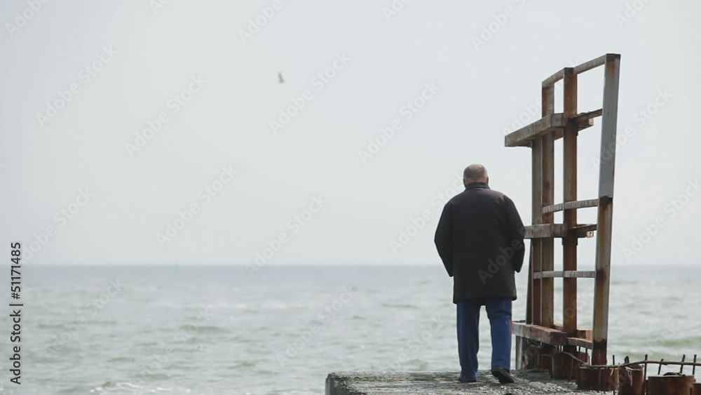 Lonely elderly man walking on the beach Lonely elderly man walking on the beach