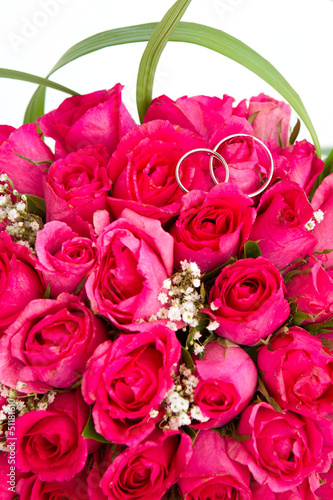 wedding rings and bridal bouquet of pink roses isolated over whi