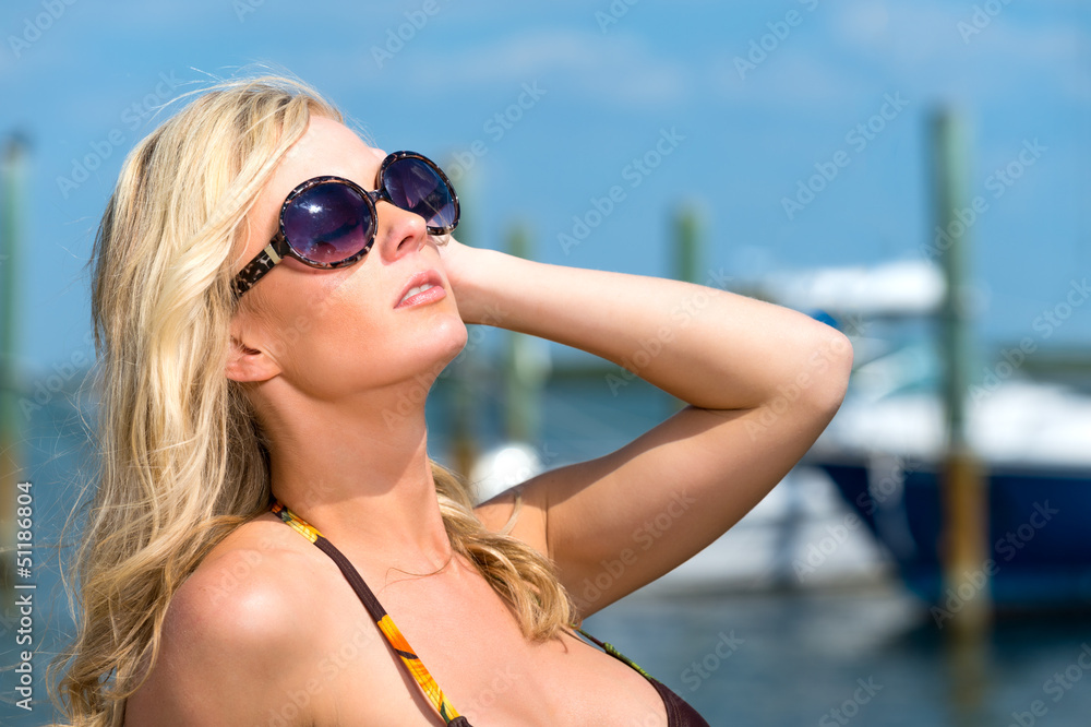 Woman enjoys the summer with boats behind.