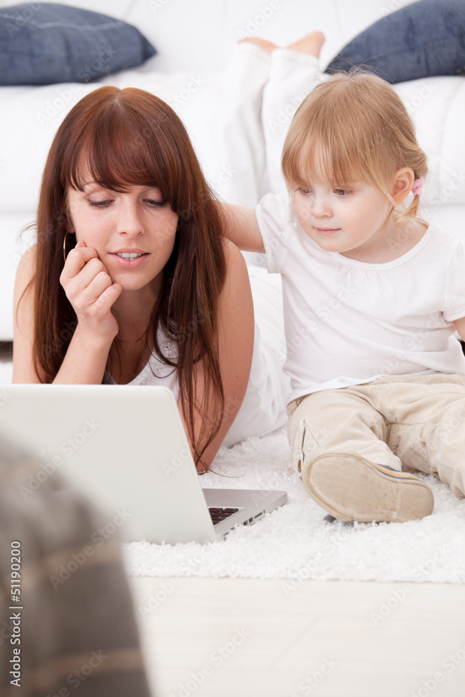Happy young mother and her daughter using a laptop Happy young mother and her daughter using a laptop