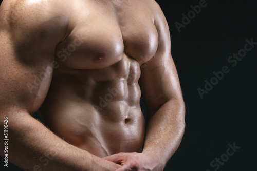 Cropped picture of muscle man posing over dark background