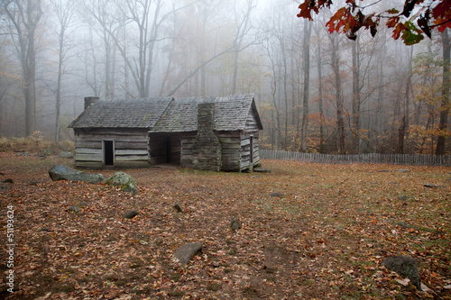 Fotografía Old log cabin in the woods with morning fog