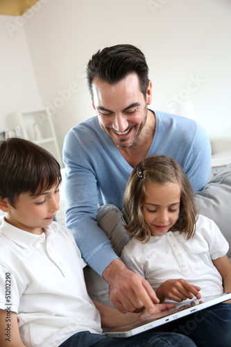 Children with daddy at home using digital tablet