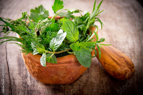Mortar with herbs on wooden table