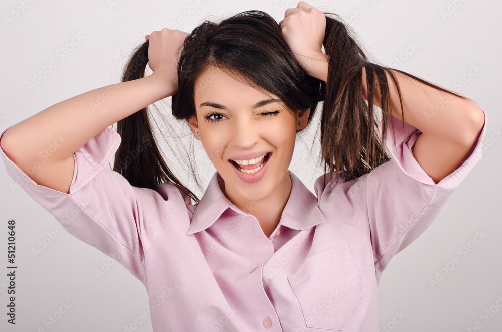 Beautiful woman winking, having fun,laughing holding her hair Beautiful woman winking, having fun,laughing holding her hair