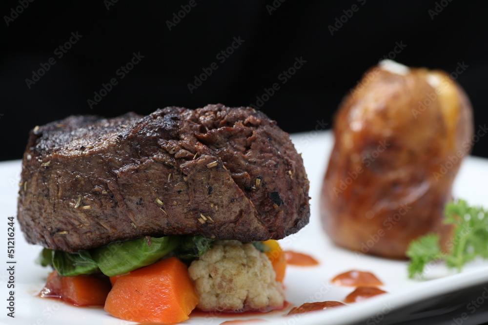 Tenderloin steak portion with potato on black background Tenderloin steak portion with potato on black background
