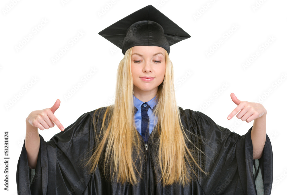 Young woman in graduation gown pointing down on copy space Young woman in graduation gown pointing down on copy space