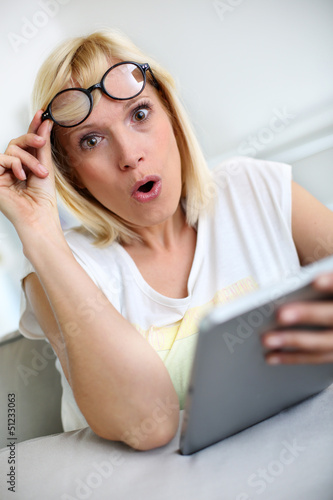 Tableau sur toile Funny girl in front of tablet with surprised look