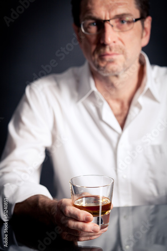 Erwachsener Mann hält ein alkoholisches Getränk in der Hand